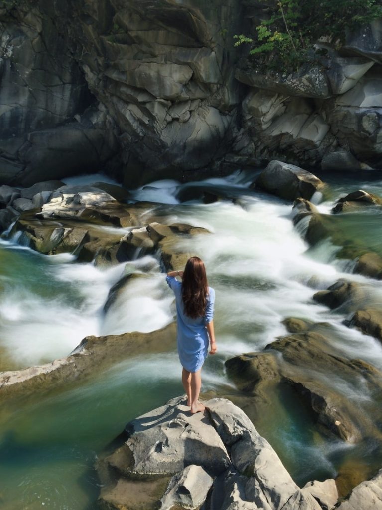 Girl in nature admiring flow of water; flow of water is similar to wu-wei in taoism